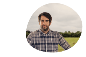 Farmer with beard wearing a checkered shirt in a field